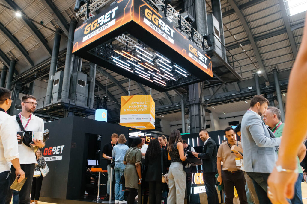 Fotografía de stand GG.BET en feria internacional con visitantes y equipo comercial